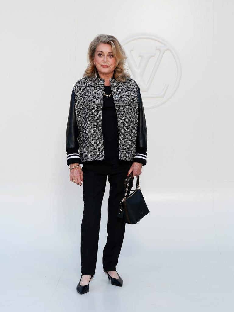 Catherine Deneuve wearing a textured Louis Vuitton varsity jacket at the Women’s Spring-Summer 2027 show in Paris.