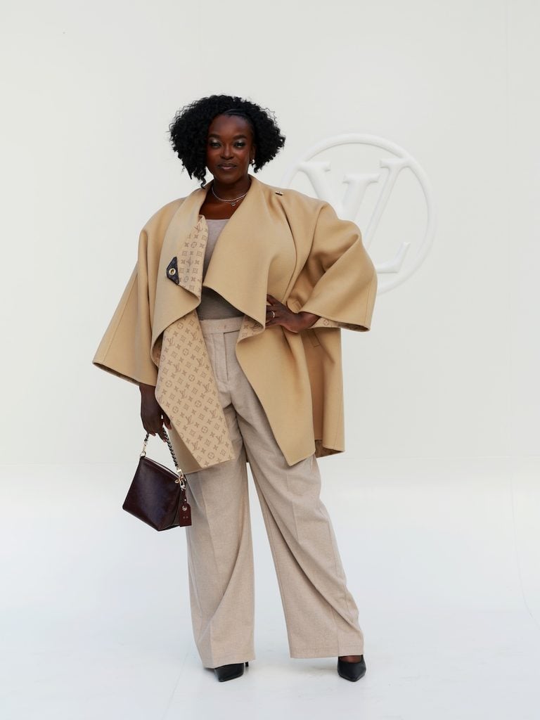 Wunmi Mosaku wearing neutral Louis Vuitton tailoring with an oversized camel wrap at the Spring-Summer 2027 show in Paris.