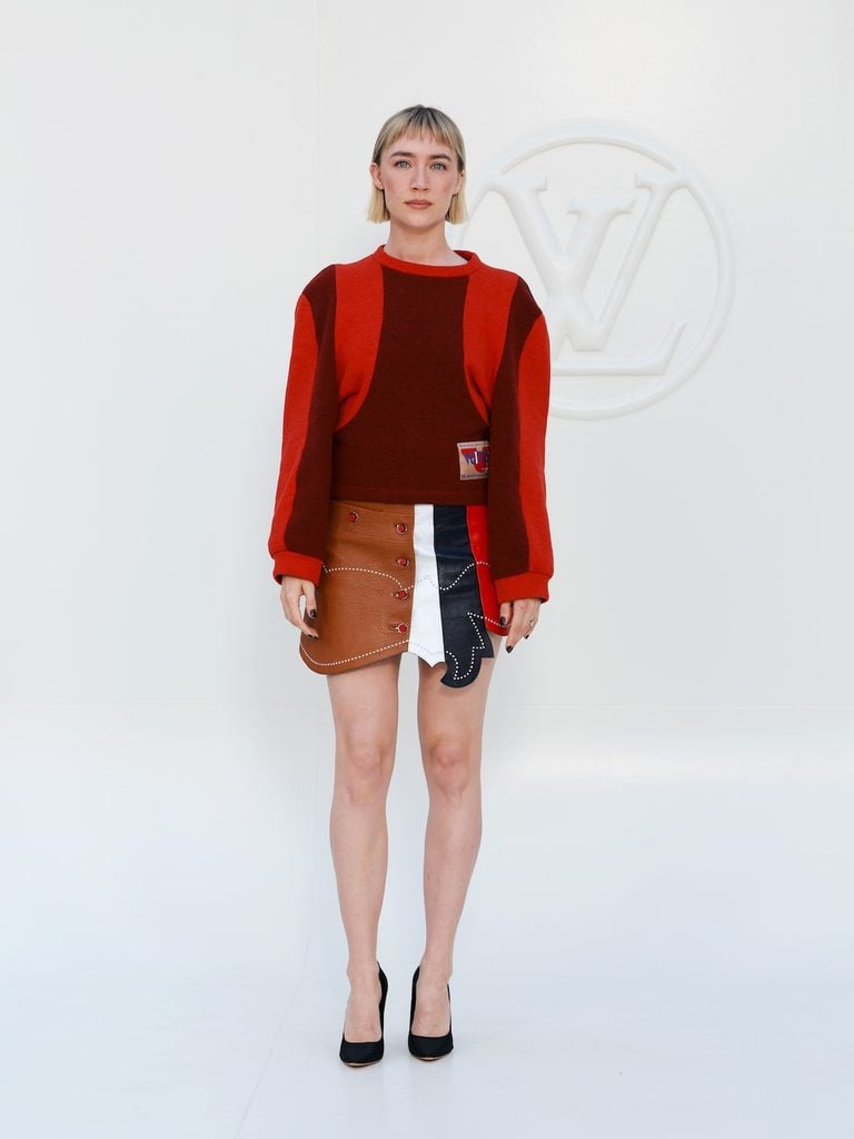 Saoirse Ronan wearing red knitwear and a colour-blocked Louis Vuitton mini skirt at the Spring-Summer 2027 show in Paris.