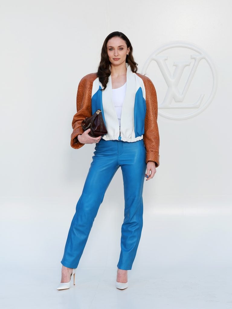 Sophie Turner wearing blue leather trousers and a colour-blocked Louis Vuitton jacket at the Spring-Summer 2027 show in Paris.