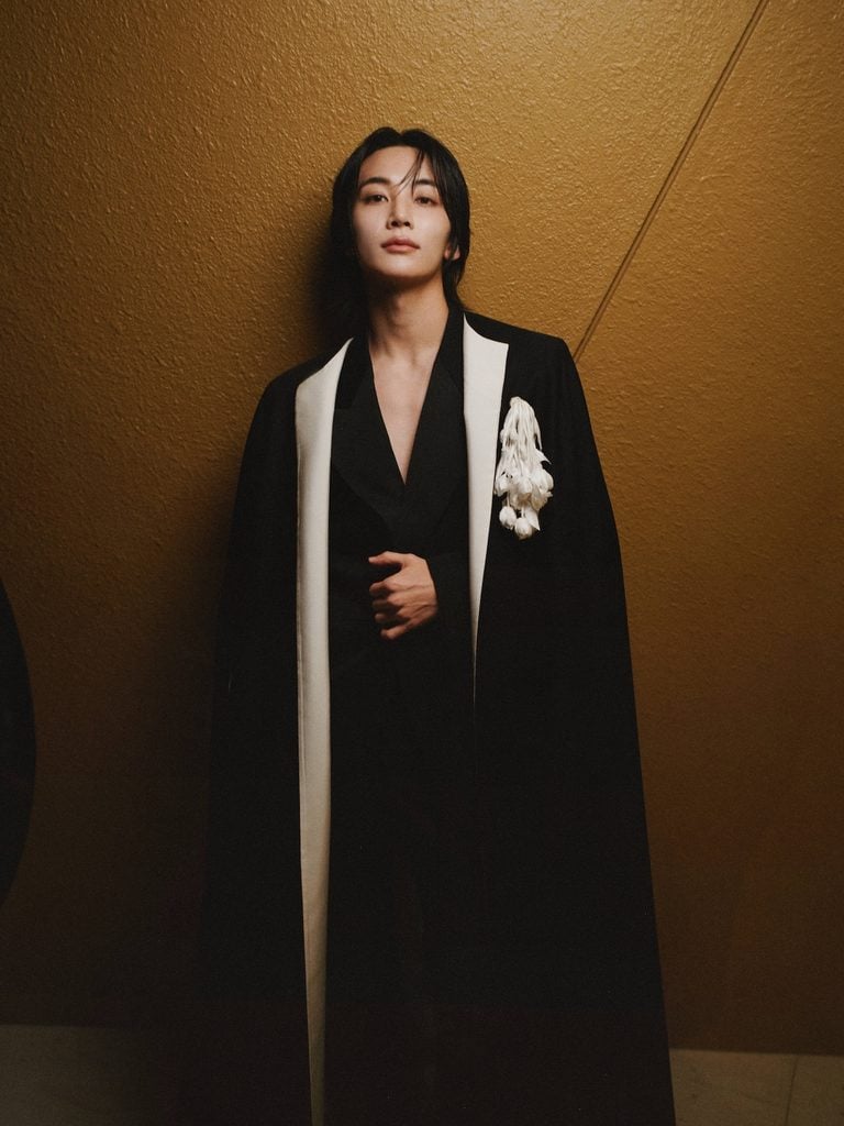 Jeonghan wearing black Givenchy tailoring with contrasting white lapels at the Givenchy Spring 2027 show in Paris.