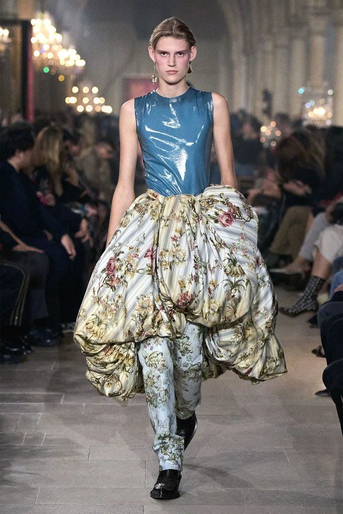 Acne Studios Spring 2027 runway model wearing a blue top with a floral skirt and matching trousers, later worn by Carrie Coon at The Gilded Age premiere.