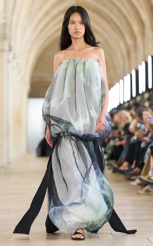 A model walks the Aje Spring 2027 runway wearing the watercolour-print strapless maxi dress with long black fabric panels later worn by Gemma Chan at the SCAD Savannah Film Festival.