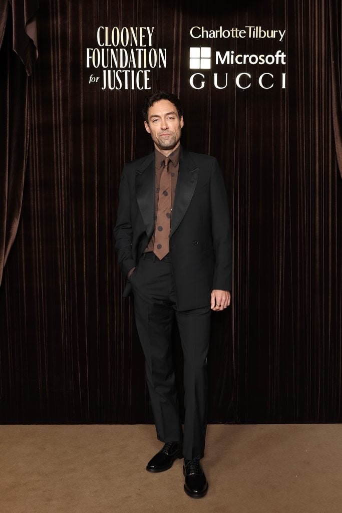 Alex Hassell in Paul Smith black evening tailoring with a brown polka-dot shirt and tie at the 2026 Albies in London