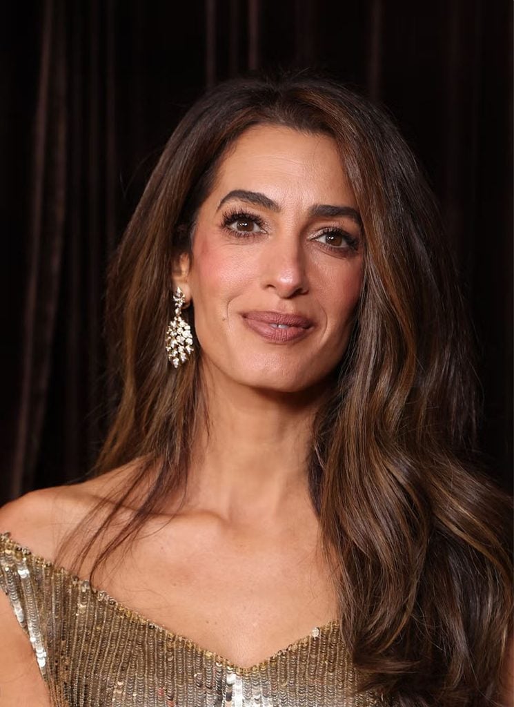 Close-up of Amal Clooney wearing Cartier diamond drop earrings with softly waved hair and a gold sequinned Gucci gown at the 2026 Albies in London.