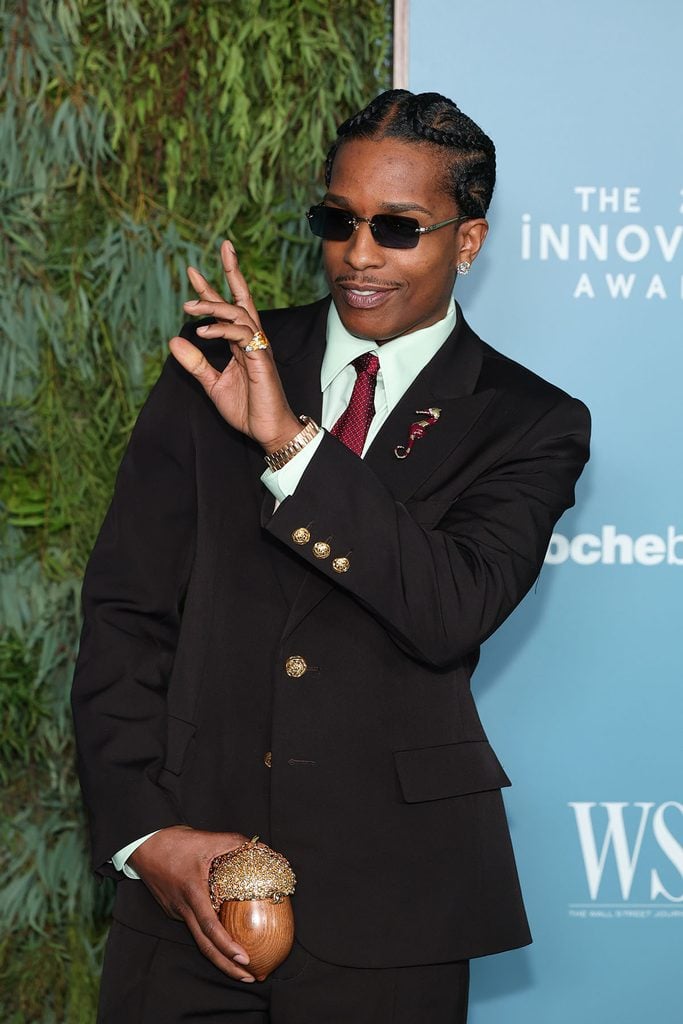 A$AP Rocky shows his Chanel Acorn Minaudière with a crystal-covered cap, burgundy tie, decorative lapel brooch and gold jewellery at the 2026 WSJ. Magazine Innovator Awards.