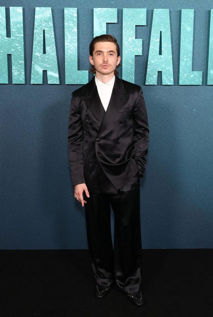 Austin Abrams wearing a custom black satin Valentino suit with studded Valentino Garavani loafers at the 'Whalefall' London premiere.