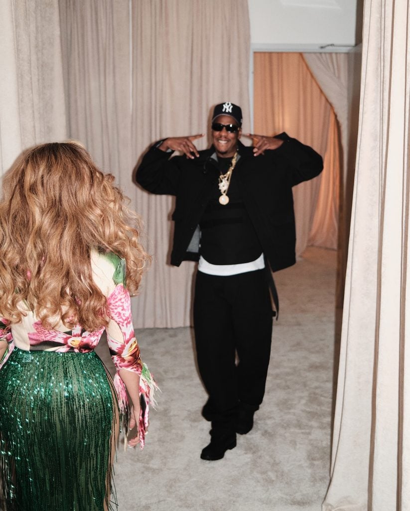 Beyoncé is photographed from behind in her emerald-green fringed skirt as JAY-Z approaches wearing black and a New York Yankees cap.
