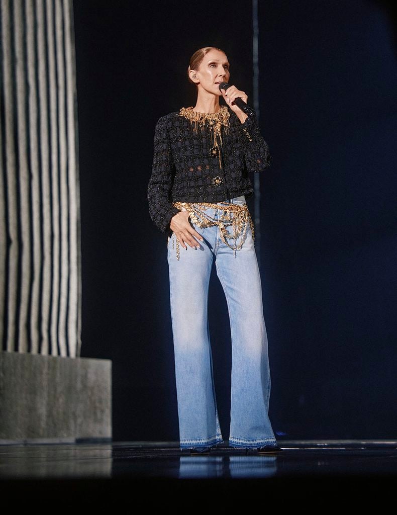 Céline Dion performs during the final night of her 2026 Paris residency wearing a black Chanel Fall 2026 Haute Couture jacket, ornate gold chain belt and light-wash wide-leg jeans.