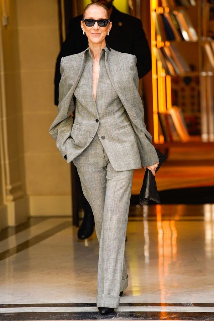 Céline Dion wearing a McQueen Spring 2027 grey checked suit with sculptural angel-wing tailoring while leaving her hotel in Paris.
