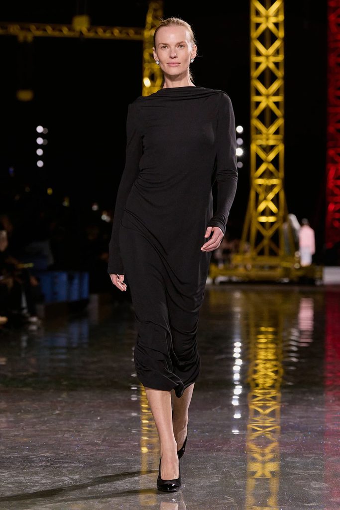 Model wearing a black draped midi dress from the Chanel Fall 2026 ready-to-wear collection on the runway.