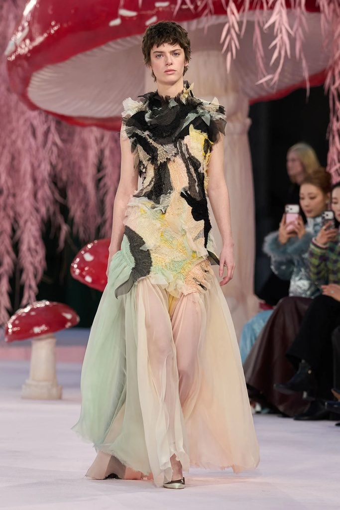 Chanel Spring 2026 Haute Couture look 25 on the runway, featuring a black and pastel textured bodice with a flowing pleated skirt, later worn by Whitney Peak to The Hunger Games: Sunrise on the Reaping London premiere.