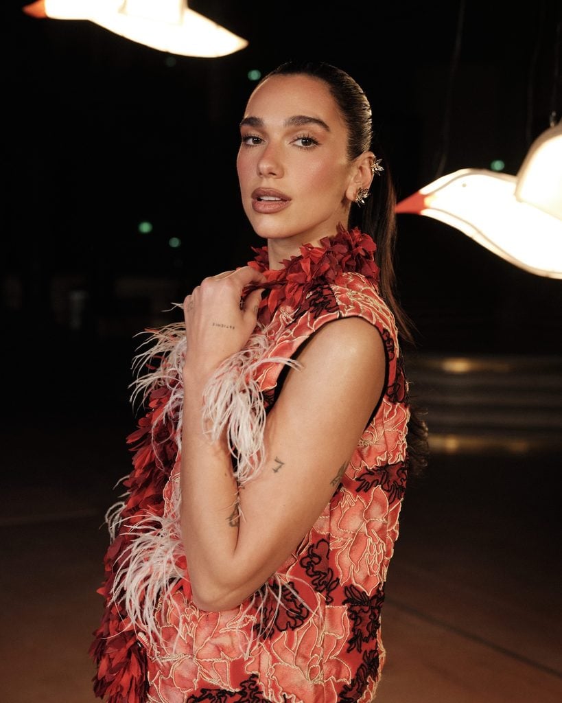 Dua Lipa front row at Chanel Womenswear Spring/Summer 2027 show in pink and red feathered dress