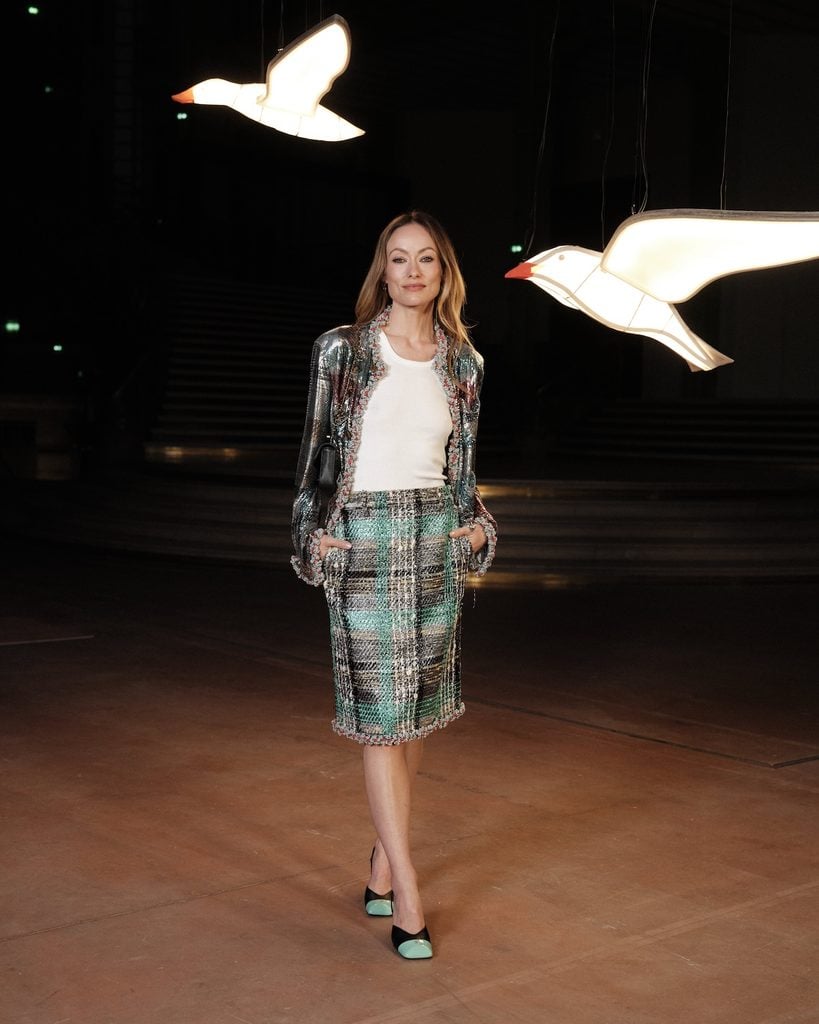 Olivia Wilde wearing a Chanel embellished jacket and checked skirt at the Chanel Spring 2027 show during Paris Fashion Week.
