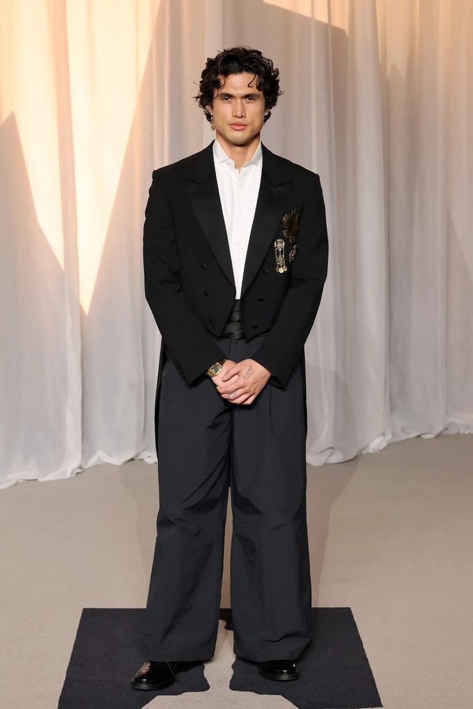 Charles Melton in an ERL Artisanal tailcoat with gold embellishments and wide-leg trousers at the Academy Museum Gala.
