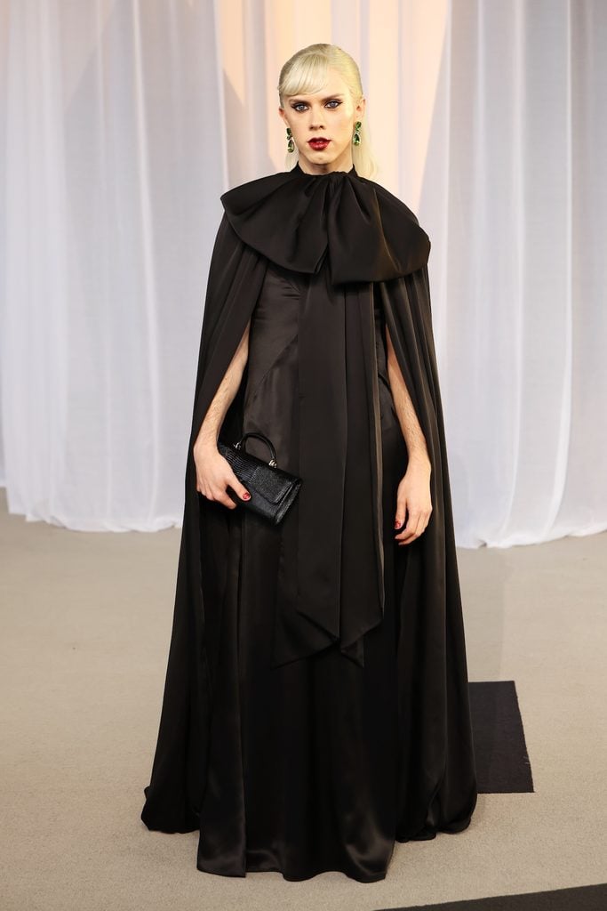 Cole Escola wearing a black Chanel cape ensemble with an oversized bow at the 2026 Academy Museum Gala