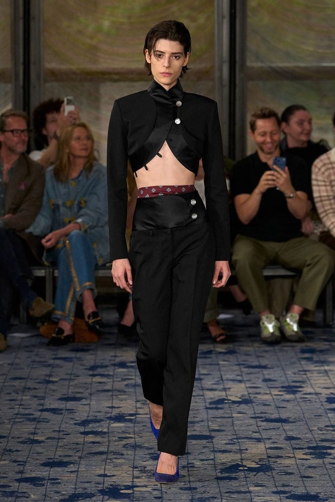 Conner Ives Spring 2027 runway model wearing the cropped black jacket and trousers later seen on Louisa Jacobson at The Gilded Age premiere in New York.