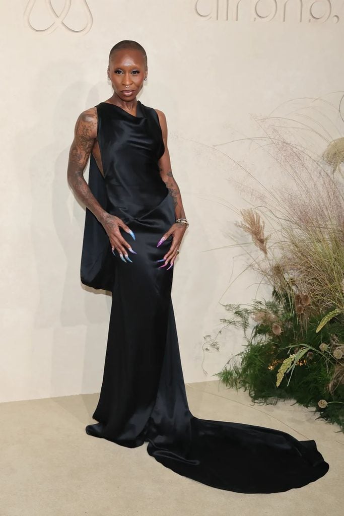Cynthia Erivo wears a sleeveless black satin gown with a draped neckline, extended train and colourful pointed nails at the 2026 Airbnb.org Gala in Los Angeles