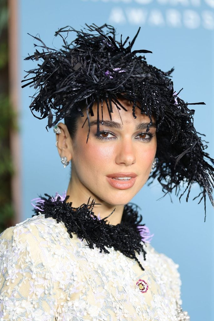 Close-up of Dua Lipa wearing an elaborate black Chanel feathered hat with purple accents, Bvlgari diamond earrings and a matching black-trimmed couture neckline at the 2026 WSJ. Magazine Innovator Awards.