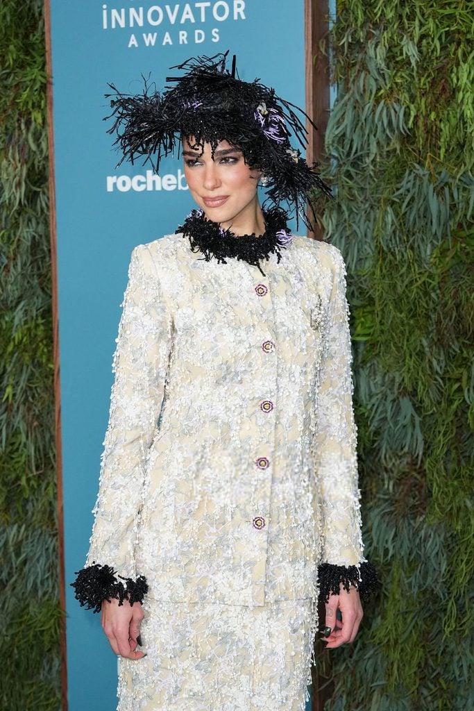 Close-up of Dua Lipa's Chanel Fall 2026 Haute Couture jacket showing intricate ivory floral embroidery, decorative buttons and black feathered neckline and cuffs.