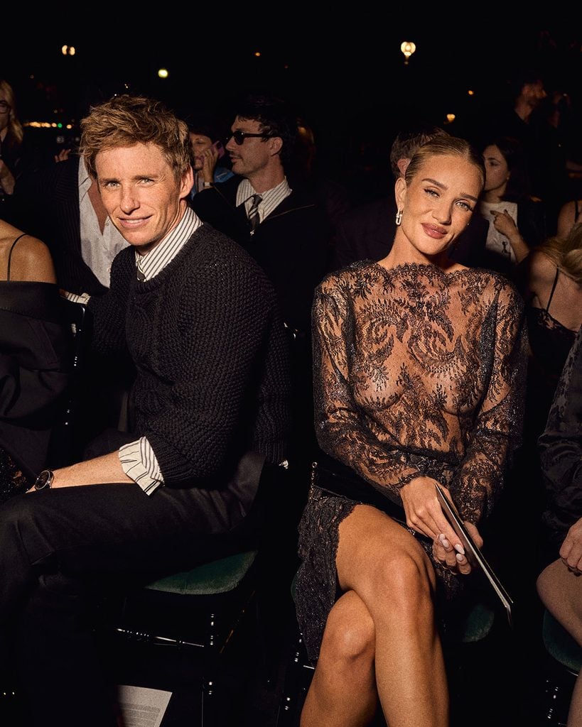Eddie Redmayne alongside Rosie Huntington-Whiteley in a sheer lace Saint Laurent dress at the Spring 2027 show in Paris.