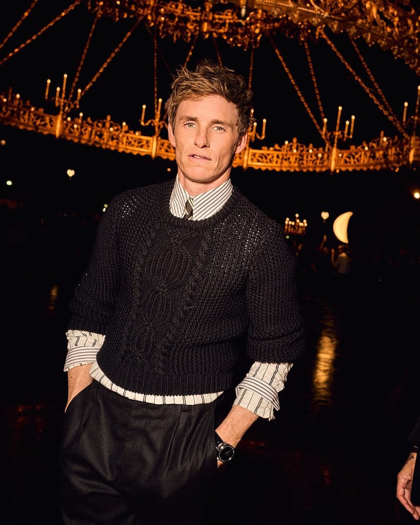 Eddie Redmayne wearing a Saint Laurent Fall 2026 knit, striped shirt and trousers at the Spring 2027 show in Paris.