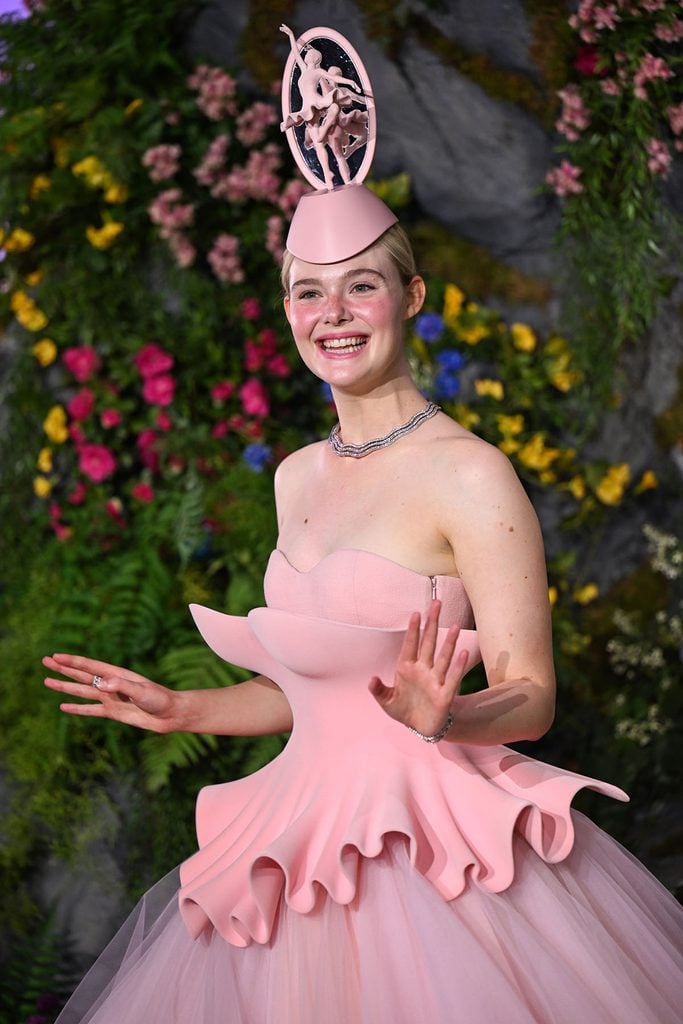 Close-up of Elle Fanning's pink Robert Wun Couture headpiece featuring a miniature ballerina framed within an oval, styled with a silver necklace at The Hunger Games London premiere.