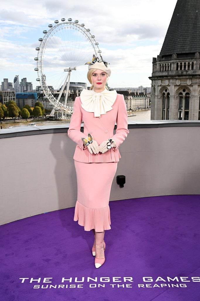 Elle Fanning in Valentino Haute Couture showing her butterfly-adorned ivory beret, oversized bow and embroidered lace glove at The Hunger Games London photocall