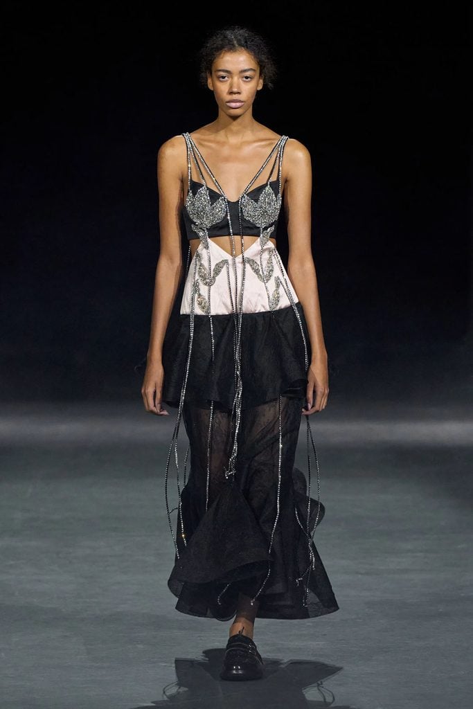 Erdem Spring 2027 runway model wears a black and pale pink collaged dress with crystal-embellished bodice, suspended beaded strands and a layered sheer black skirt.