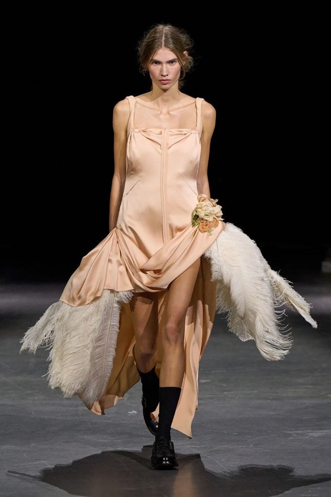 Model wearing the Erdem Spring 2027 peach satin feather-trimmed dress on the runway.