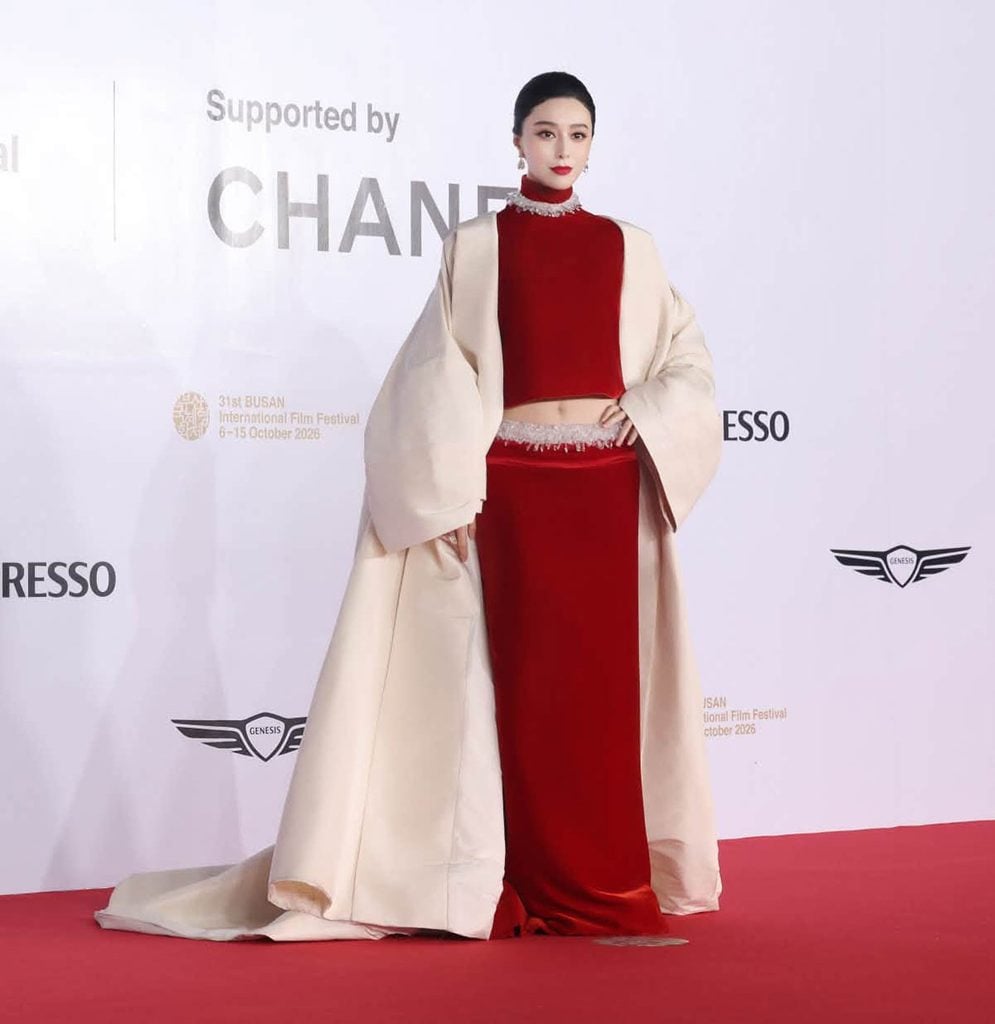 Fan Bingbing wearing red velvet Stéphane Rolland Haute Couture with a dramatic ivory coat at the 2026 Busan International Film Festival.