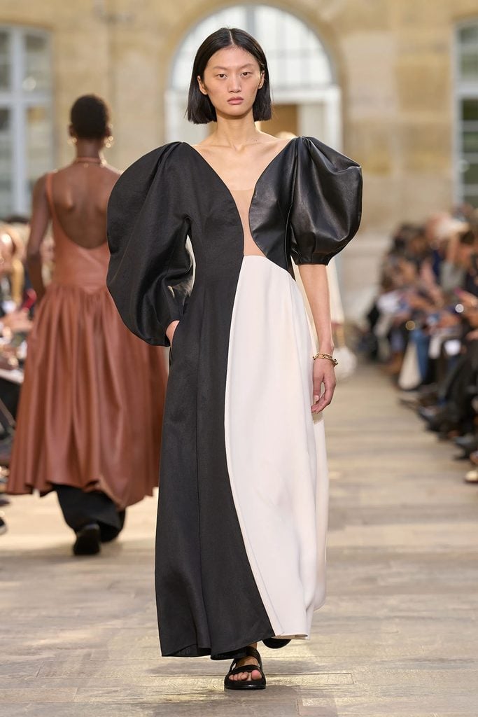 Gabriela Hearst Spring 2026 runway model wearing the black and ivory asymmetric Sephir dress with sculptural sleeves