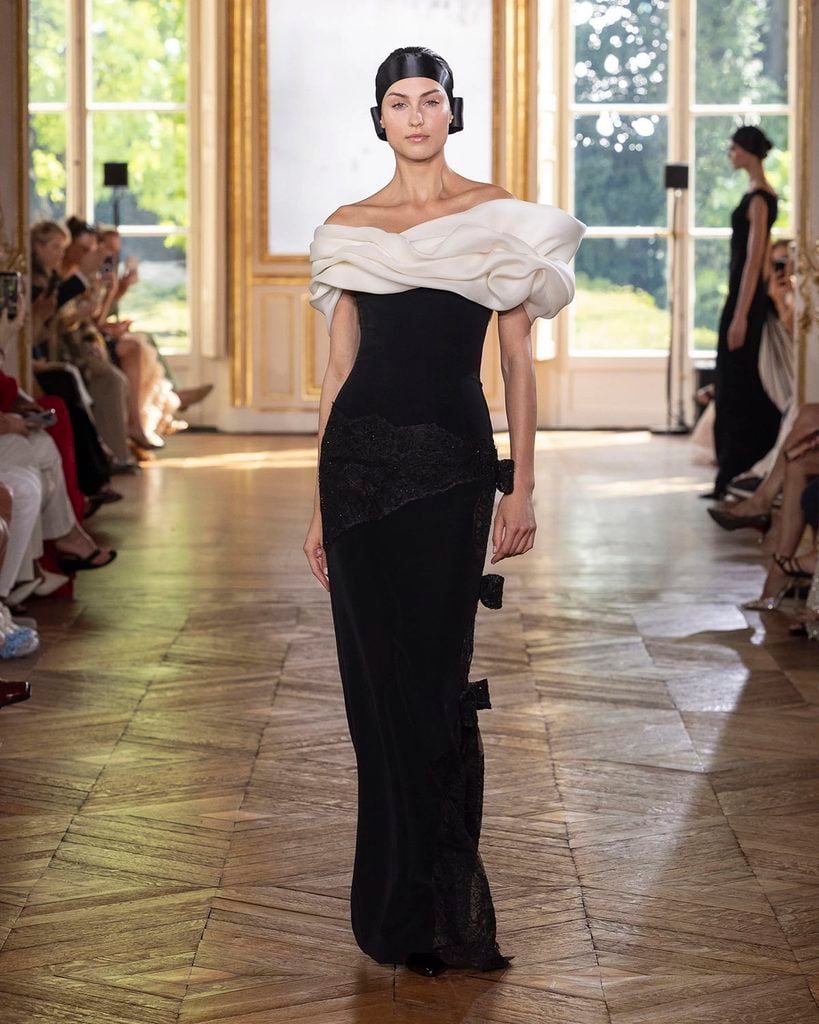 Georges Chakra Fall 2026 Couture runway model wearing a black column gown with an ivory sculptural neckline and asymmetric lace detailing.