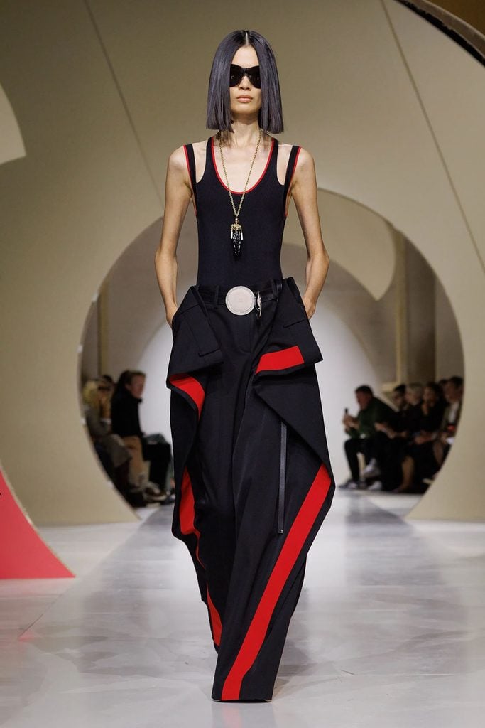 Givenchy by Sarah Burton Spring 2027 runway look 47 featuring a black knitted vest and red-trimmed trousers