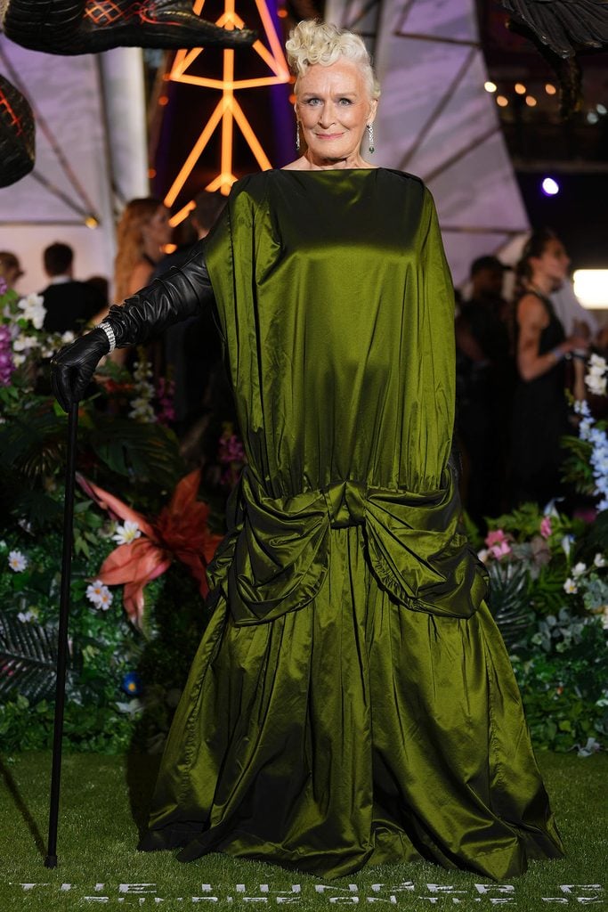 Glenn Close wears a moss-green Simone Rocha Fall 2026 taffeta gown with gathered bow detailing, a black leather glove and cane at The Hunger Games: Sunrise on the Reaping London premiere.