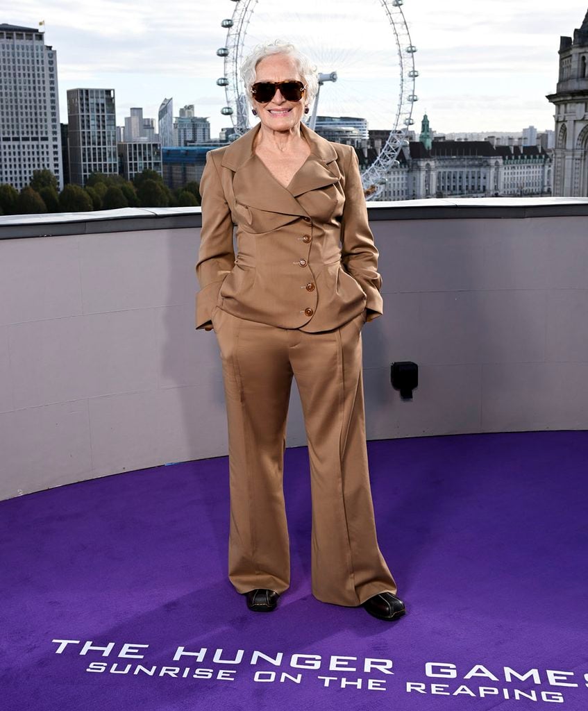 Glenn Close poses with her hands in her pockets wearing a camel-coloured Vivienne Westwood trouser suit, sunglasses and Dr. Martens boots at the London photocall.