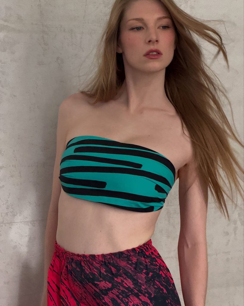 Close up of Hunter Schafer wearing a turquoise striped Prada bandeau top, pink printed skirt and black mules for the 'Blade Runner 2099' presentation at New York Comic Con