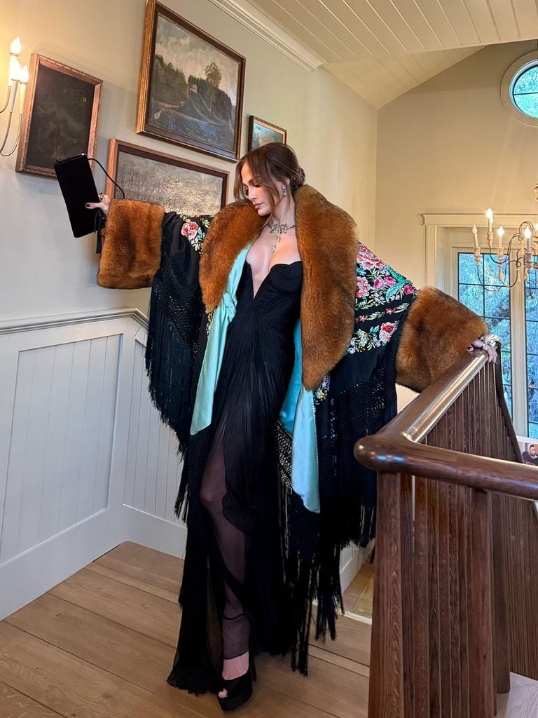 Jennifer Lopez posing on a staircase in a plunging black Maria Lucia Hohan gown and embroidered Dolce & Gabbana Alta Moda coat with sweeping fringe ahead of the LA Opera 2026 Opening Night Gala.