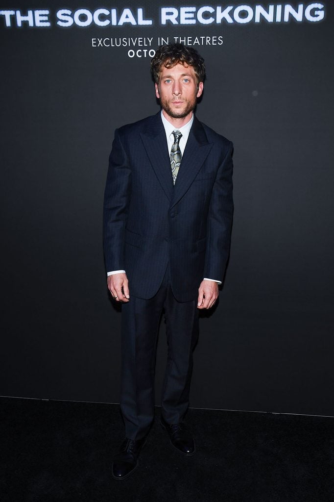 Jeremy Allen White wearing a custom Louis Vuitton navy pinstripe suit with a snake-print tie at 'The Social Reckoning' New York premiere.
