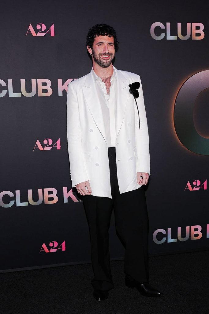 Jordan Firstman attends the Club Kid New York premiere in a white TOM FORD by Haider Ackermann double-breasted jacket with a black floral brooch.