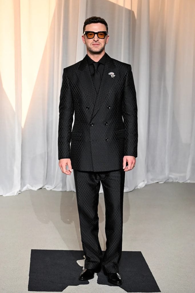Justin Timberlake wearing a patterned Tom Ford suit with a Tiffany & Co. floral brooch and tinted sunglasses at the Academy Museum Gala.