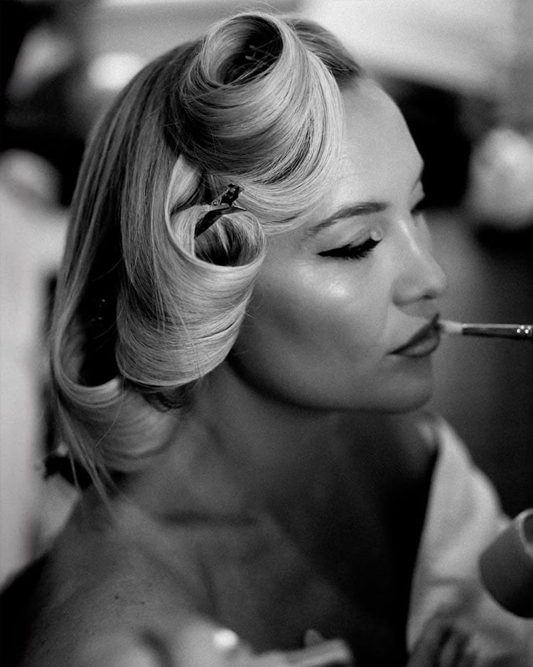Black-and-white backstage photograph of Kate Hudson with pinned blonde curls and sculpted waves while preparing for the Academy Museum Gala.