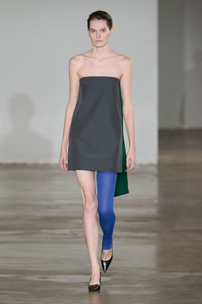 LII Spring 2027 runway look featuring a strapless grey mini dress with a green side panel and single blue legging.
