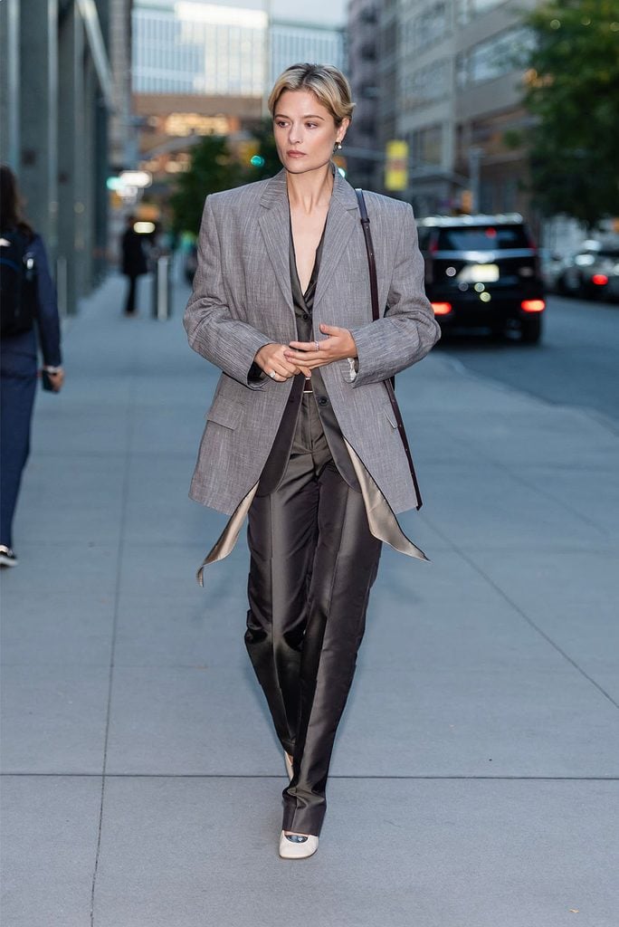 Louisa Jacobson wearing a grey Calvin Klein Collection Spring 2027 tailored ensemble with an oxblood bag in New York ahead of Good Morning America.