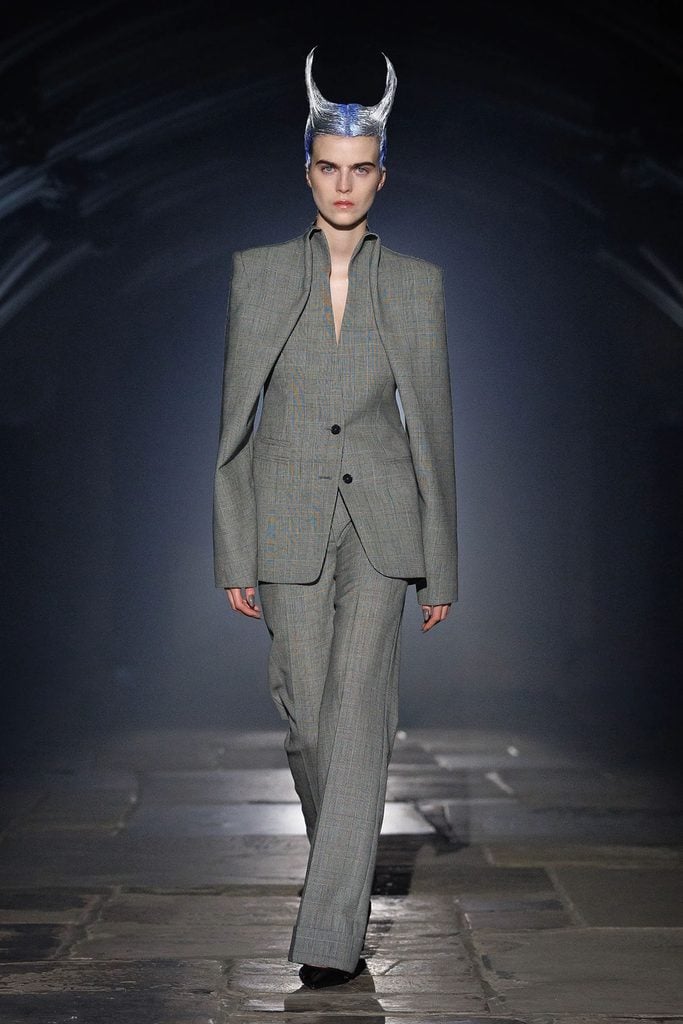 Model wearing a grey Prince of Wales check angel-wing tailored jacket and wide-leg trousers on the McQueen Spring 2027 runway.