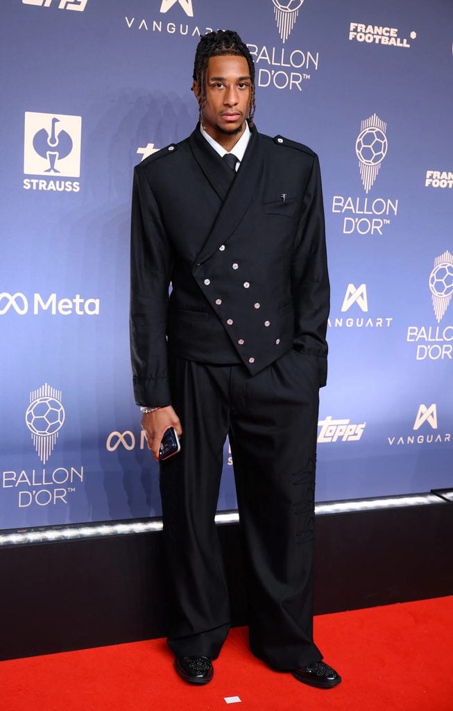 Michael Olise in an asymmetric black Yaku suit with military-inspired buttons at the 2026 Ballon d'Or Awards.