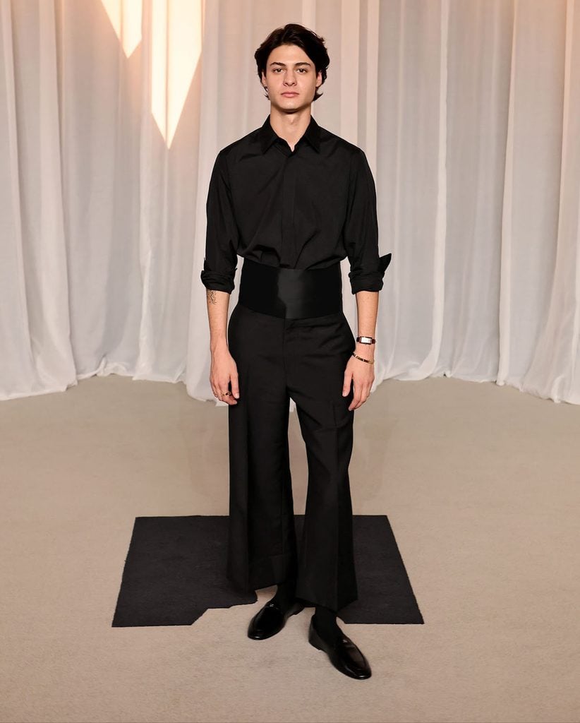 Milo Quifes in a Celine black shirt, cropped flared trousers and satin cummerbund at the 2026 Academy Museum Gala.