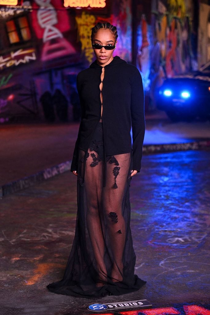 Naomi Ackie wears a black Colleen Allen Fall 2026 cardigan and sheer embroidered skirt at the Clayface London photocall.