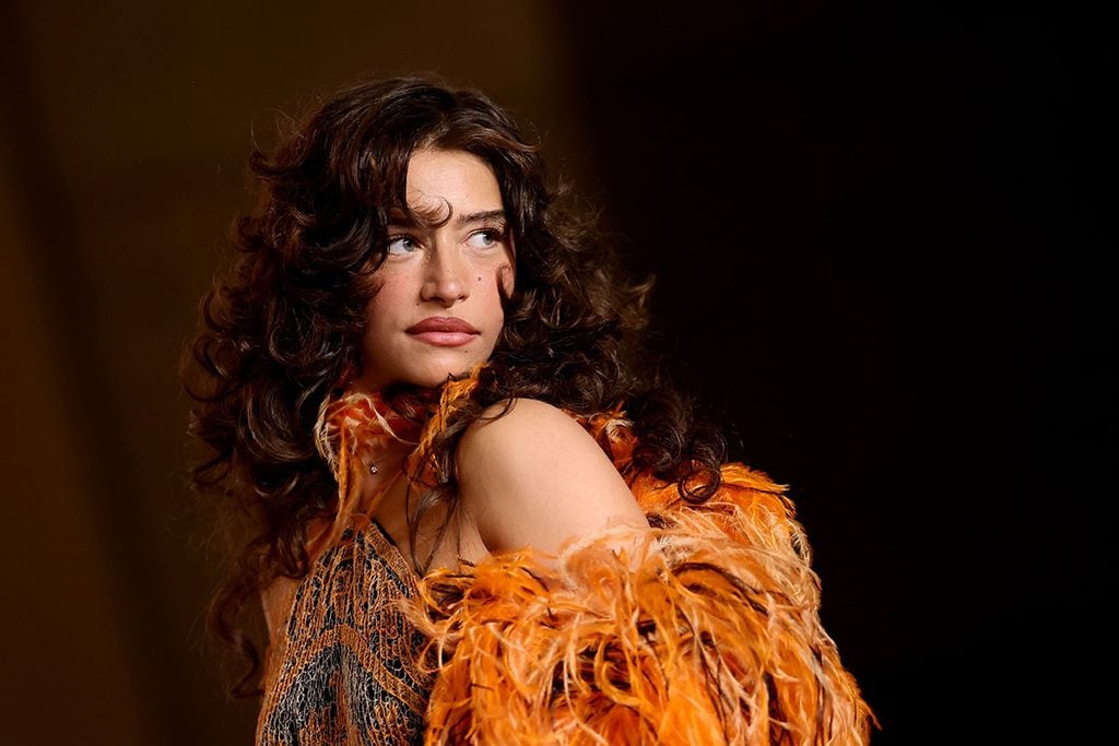 Close-up of Odessa A’zion's orange feathered Giorgio Armani Privé look and curly hairstyle at the Academy Museum Gala