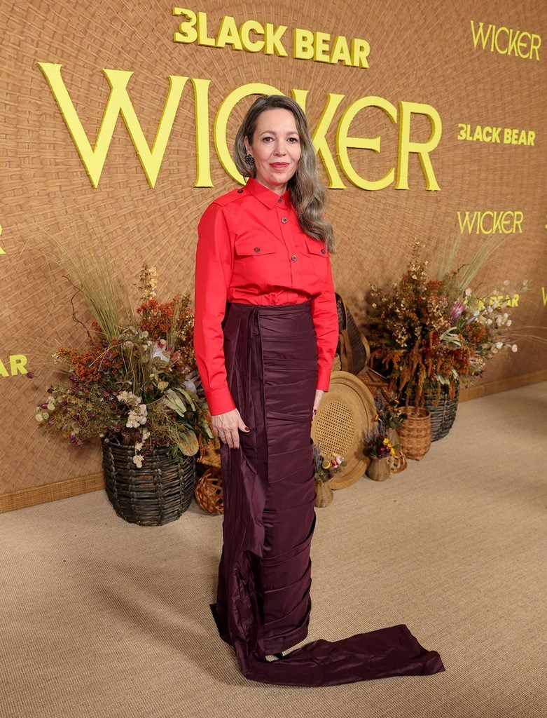 Olivia Colman in a red Prada shirt and burgundy taffeta skirt at the Wicker Los Angeles premiere in 2026.